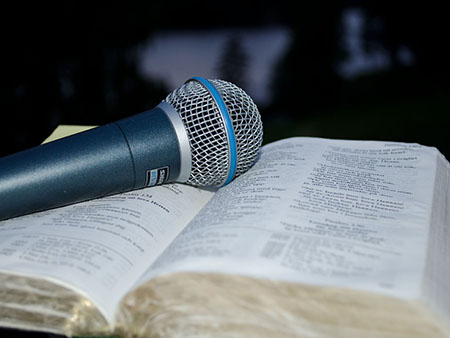 Un micrófono puesto sobre una Biblia abierta ilustra el mensaje radial Nacer de Nuevo.