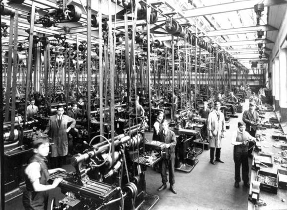 Fotografía de una gran fábrica con muchísima maquinaria y muchos empleados, en blanco y negro, al principio de la Edad Industrail.