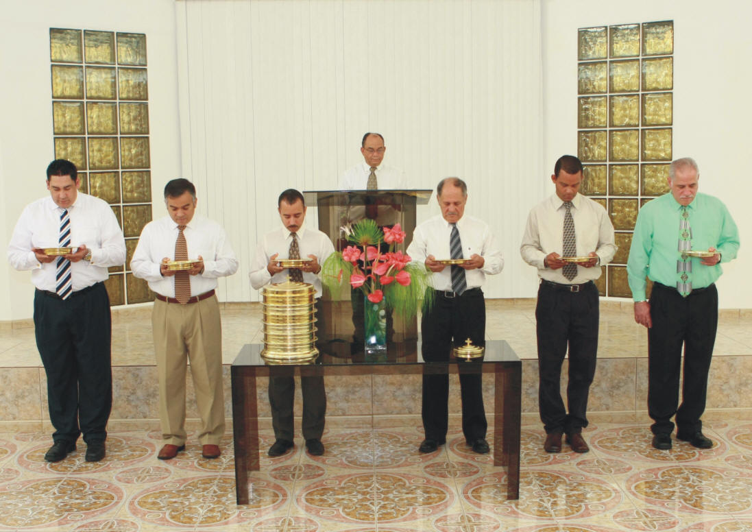 Fotografía de siete varones de la Iglesia de Cristo, Alturas de Flamboyán, Bayamón, Puerto Rico que en el acto de oficiar la Cena del Señor conforme a las directrices del Nuevo Testamento.
