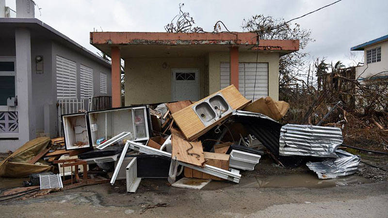 Muebles y enseres dañados, más planchas de zinc y otros escombros, amontonados frente a una casa de Punta Santiago, cerca del mar en el este de Puerto Rico, fruto del azote del huracán María.