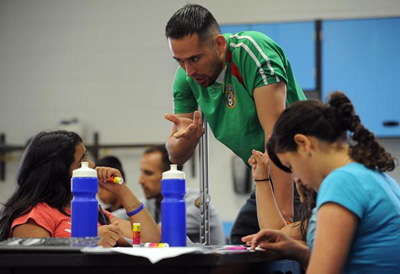 Maestro latino enseña a adolescentes en una escuela pública.
