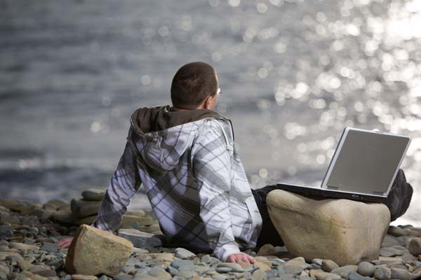 Esta fotografía de un varón sentado frente a aguas, con su computadora al lado, ilustra la Lista de temas ilustrados Meditaciones y lecciones bíblicas ilustradas, en editoriallapaz.