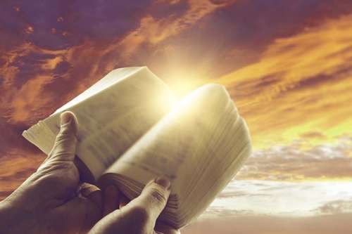 Gráfica de manos que sostienen una Biblia abierta contra un trasfondo de nubes de tonos anaranjados, amarillos y pardos, ilustración para la Comentarios sobre 2 Timoteo, lista de archivos relevantes.