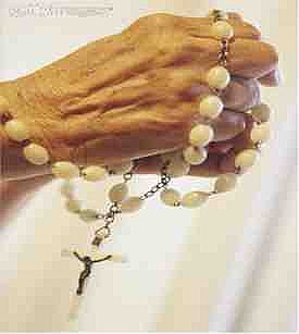 Fotografía de manos masculinas que sostienen un rosario conforme a las tradiciones de la Iglesia Católica Romana.