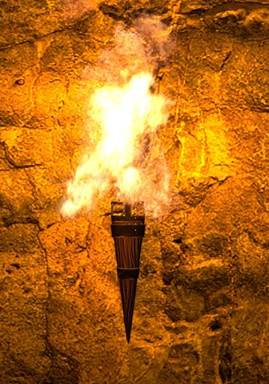 Una fotografía de una antorcha encendida pegada a un muro antiguo.