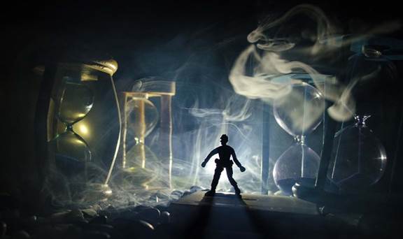 Fantástica imagen abstracta de una figura humana como de ladrón rodeado de linternas y relojes de arena, iluminado de pronto la figura por una luz blanca fuerte, sorprendido sobre manera el ladrón. 
