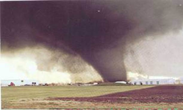 Una fotografía de un tornado grandísimo sobre campos llanos.
