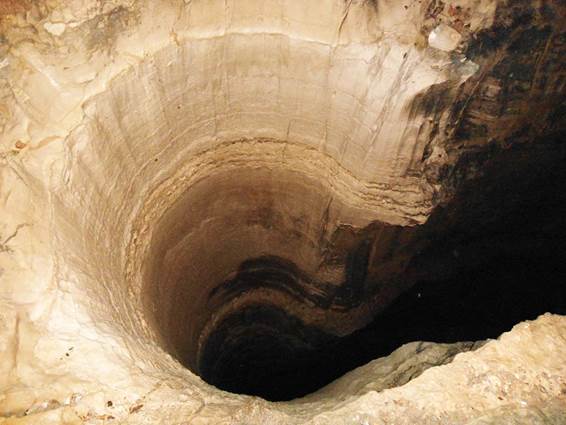 La fotografía de un gran pozo profundo del sale humo negro ilustra el tema Humo sale del pozo de abismo según el video de la Quinta Trompeta de Apocalipsis.