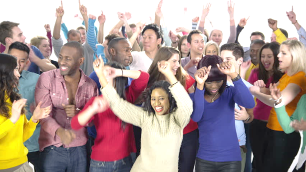 Foto de personas de distintas razas paradas con sus brazos levantados y riendose.