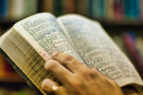 Foto de una Biblia abierta en manos de una persona que la lee.