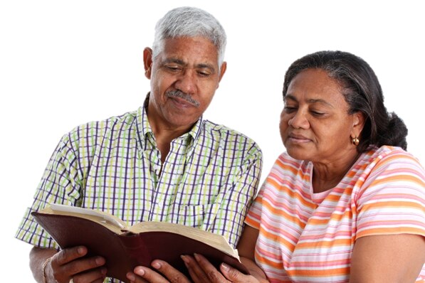 Foto de una pareja hispana de edad que estudian juntos la Biblia.