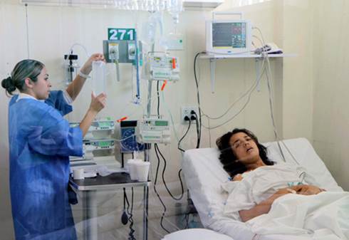 Esta fotografía de una dama joven recostada en un hospital mientras le atiende una enfermera, ilustra el tema Eterna salud, en editoriallapaz.