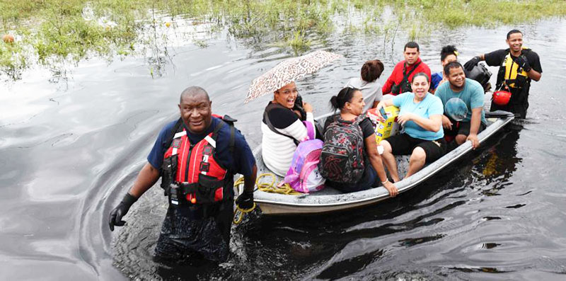 Barrio Miñi Miñi, Loiza, Puerto Rico. ¡Riéndose en medio de la tragedia! ¿Y por qué no? ¡Están vivos! Están siendo rescatados por dos varones fuertes que hacen una obra digna de admiración. Rescatados de las inundaciones causadas por las lluvias torrenciales del huracán María. Barrio Miñi Miñi, Loiza, Puerto Rico. No, that is not a mistake in the name of the barrio. “Miñi Miñi” is correct. Pronounce the “ñ” like a “y,” and you should get close to saying the name like it should be said. Smiling and laughing in the midst of tragedy! And, why not? They are alive! They are being rescued from flood waters of hurricane Maria by two stout men doing a job truly worthy of admiration.
