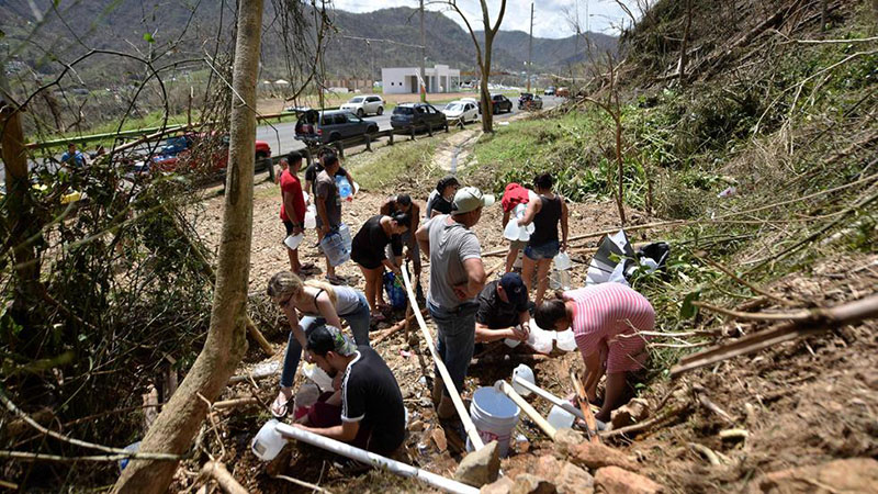 ¡Bendición en medio de sufrimiento y escasez! En Naranjito, Puerto Rico, área montañosa, un derrumbe descubre una manantial de aguas potables y las gentes la aprovechan metiendo tubos para recoger el preciado líquido.