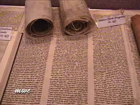 Dos rollos encima de un manuscripto antiguo representan los documentos inspirados que componen el Nuevo Testamento.