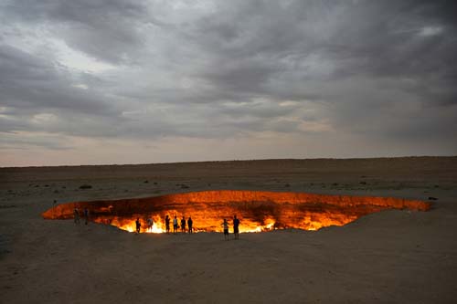 Esta imagen de un hoyo de fuego con algunas personas paradas en la misma orilla, en medio de un paisaje solitario bajo cielos grisáceos, ilustra el mensaje La Boca del Infierno, en editoriallapaz.