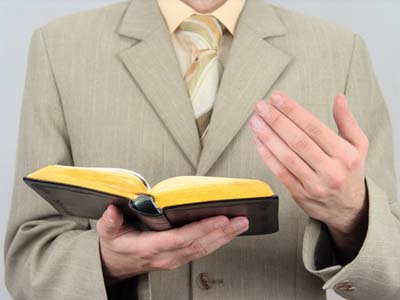 Esta fotografía de un predicador que sostiene la Biblia abierta en sus manos ilustra el ensayo Predicar doctrina, ¡NO! Solo el “corazón del evangelio”, en editoriallapaz.org.
