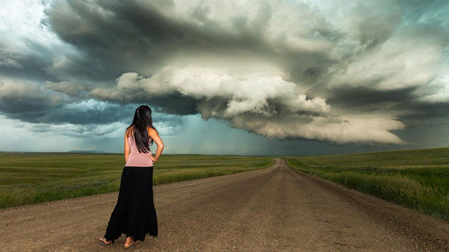 Esta fotografía de una dama parada en un camino frente a nubes bajitas y amenazantes que se acercan rápidamente hacia ella ilustra el tema Mucho miedo ante los pensamientos malos, en editoriallapaz.org.