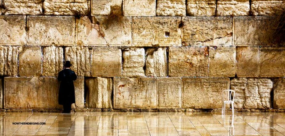 A solitary Jewish man stands before the Western Wall, or Wailing Wall, beautifully illuminated in tones of gold and brown, a photograph illustrating the subject Jews Today: Missing Out?