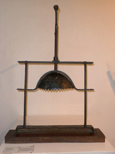 Mecanismo diabólico utilizado por la Inquisición Católica Romana para torturar a acusados de herejía. La víctima fue forzada a colocar la cabeza entre las piezas de tal manera que la barbilla descansara sobre la madera. Luego, el verdugo, dando vueltas a  la tuerca en la parte superior, hacía que la pieza cóncava bajara poco a poco, presionando cada más fuertemente el cráneo, la quijada y demás huesos de la cabeza, hasta romper primero los dientes, entonces otros huesos, finalmente causando la muerte al romperse los huesos del cráneo. 