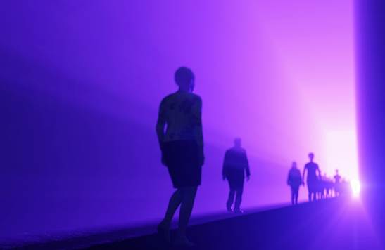 Backview of human figures in silouette moving through purplish light toward a white light in the distance in representation of souls on their way to meet Christ in the clouds.
