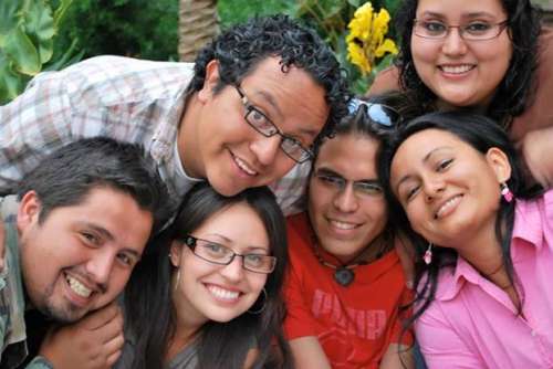 Fotografía closeup de las caras de tres damas y tres varones latinos, todo sonrientes, para el ensayo sobre El color de vida humana.